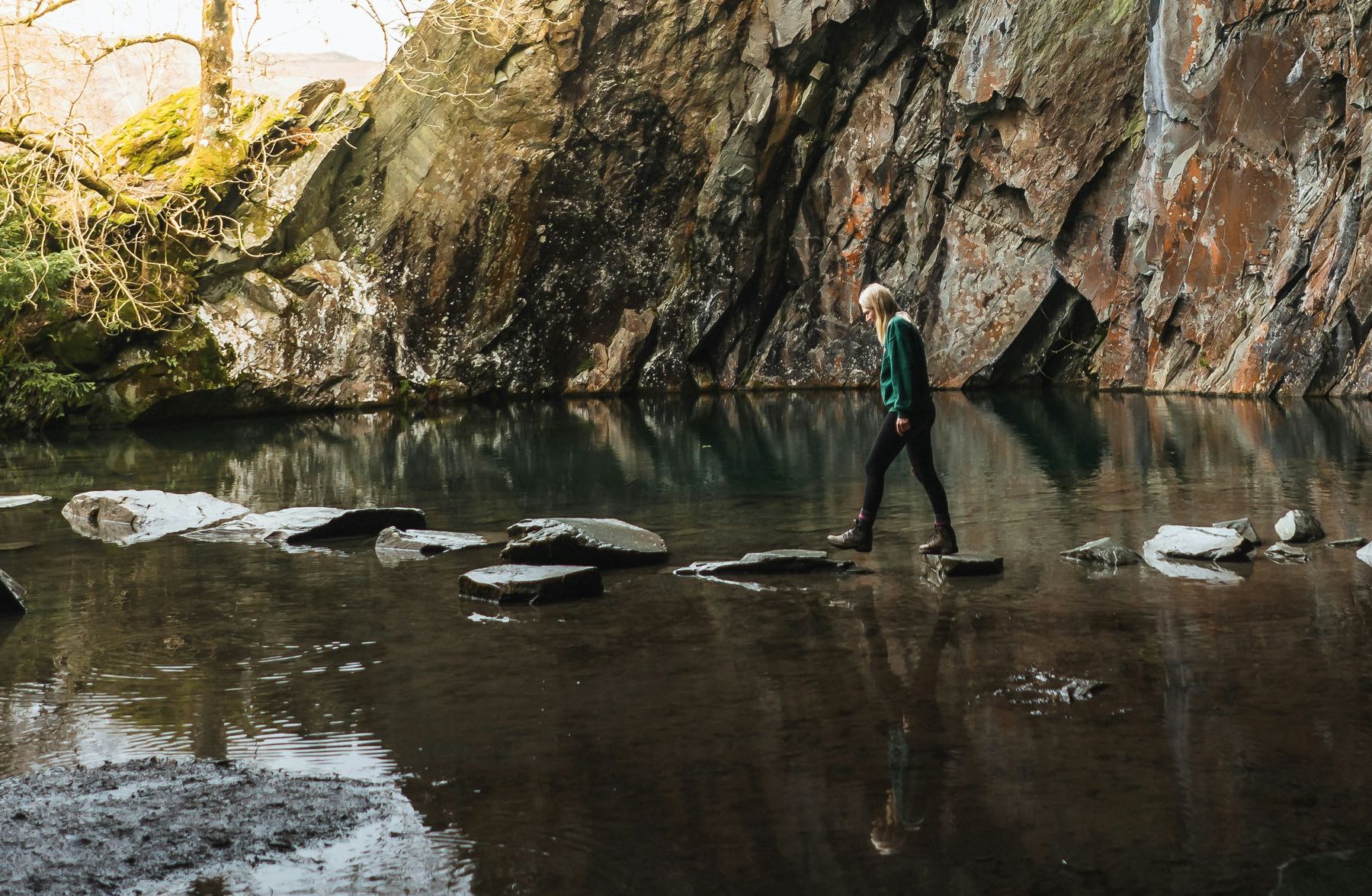 Man walks on stones that make a path in the water.
